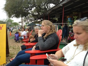 People watching at the Campbell Building in Warrenton, Texas.  (left to right) Beth Brown-holding Queen of Heirs mascot Peaches-Maggie studying the crowd and Emma texting.@Jean Janssen