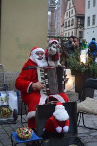 Santa busker, Rothenburg, Germany.  Santa's dog is real and walked around on his shoulder while he played and sang Christmas carols. ©Jean Janssen